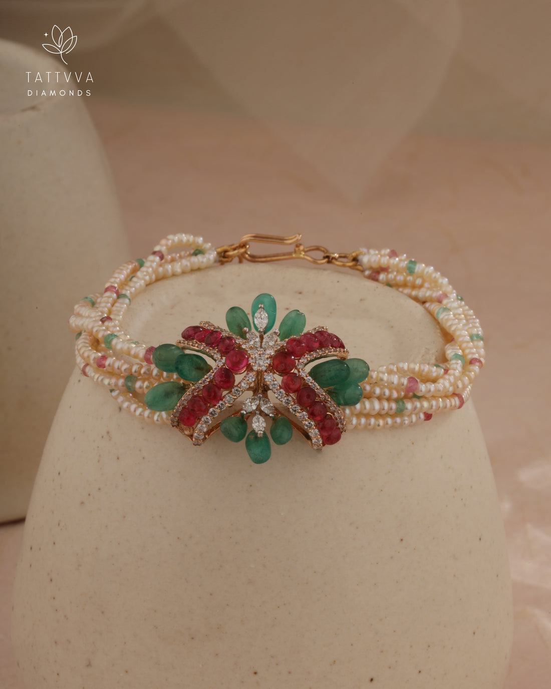 Delicate bracelet with green and red gemstones on a beige background