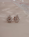 Pair of diamond earrings on a soft pink background with Tattvva Diamonds logo.