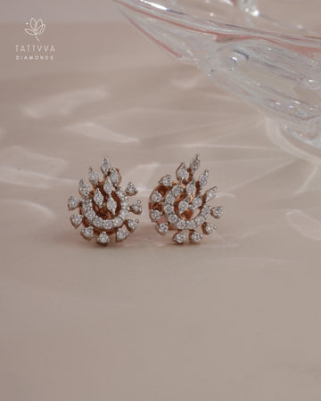 Pair of diamond earrings on a soft pink background with Tattvva Diamonds logo.