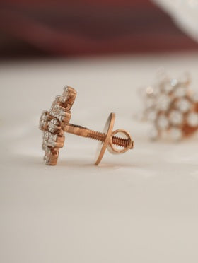 Rose gold earring with clear gemstones on a light background