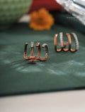 Rose gold earrings on a green surface with a blurred background