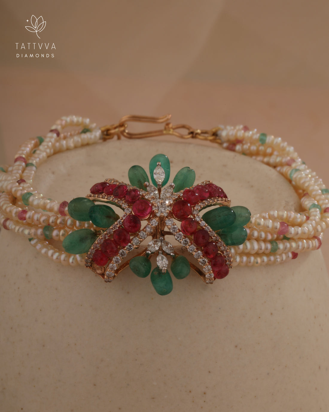 Delicate bracelet with green and red gemstones on a beige background