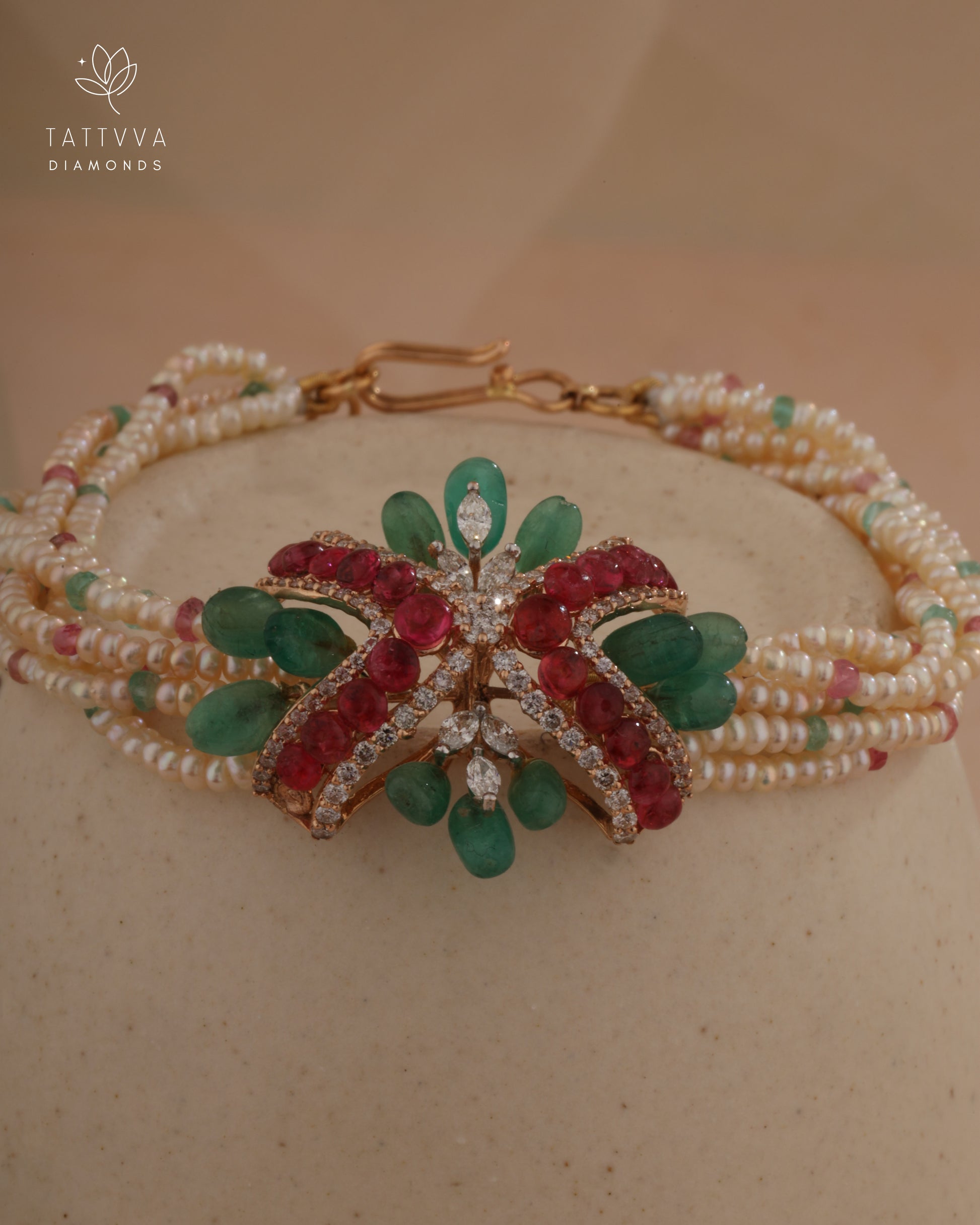 Delicate bracelet with green and red gemstones on a beige background