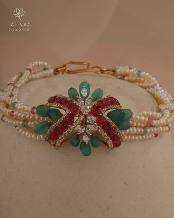 Delicate bracelet with green and red gemstones on a beige background