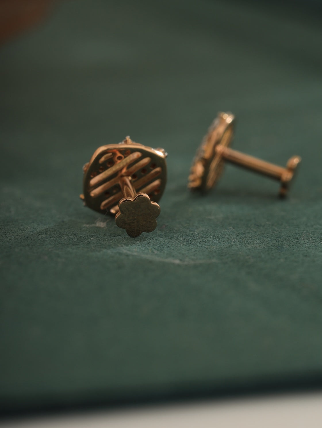 Pair of bronze earrings on a green fabric background