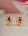 Gold earrings with red gemstones on a light background