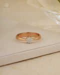 Rose gold ring with a diamond on a beige surface, branded 'Tattvva Diamonds'.