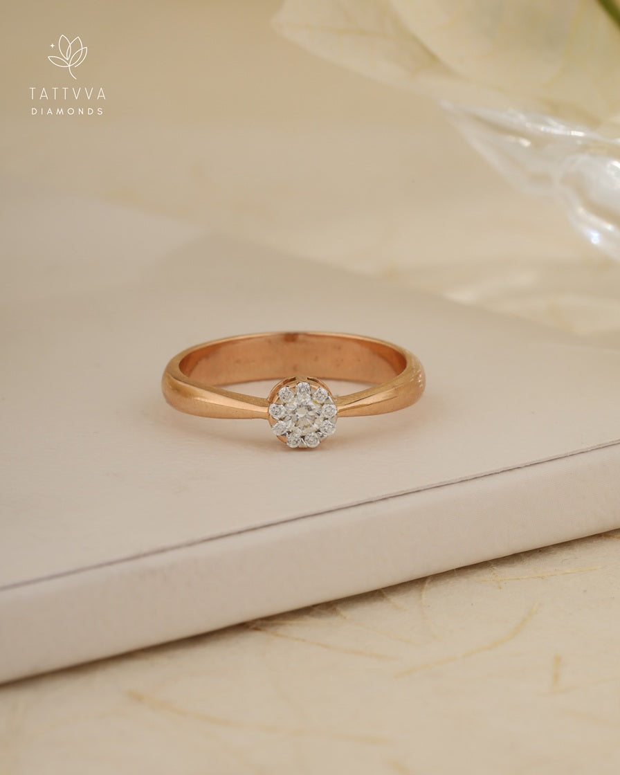 Rose gold ring with a diamond on a beige surface, branded 'Tattvva Diamonds'.