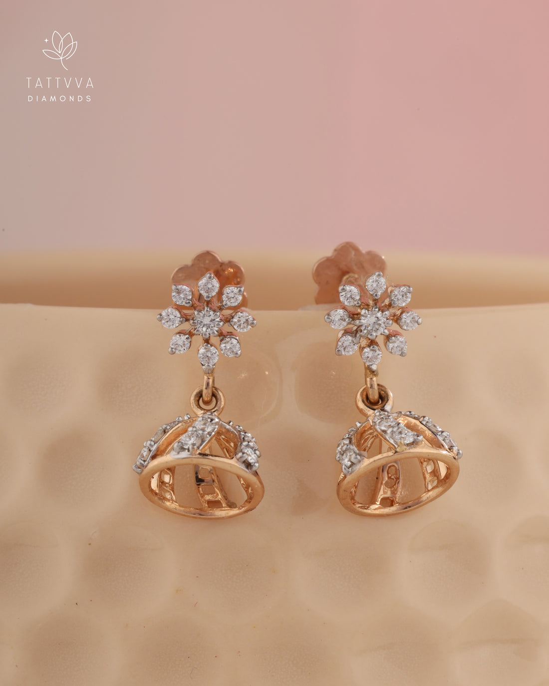 Rose gold earrings with diamond accents on a beige background, branded with Tattvva Diamonds.