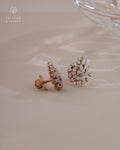 Rose gold diamond earrings on a light pink surface with Tattvva Diamonds logo.