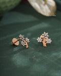 Rose gold earrings with diamond accents on a green leaf, branded 'Taraiva Diamonds'.