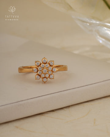Gold ring with diamond accents on a beige surface, branded 'Tattvva Diamonds'.