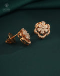 Rose gold earrings with diamond accents on a dark green fabric background, featuring Tattvva Diamonds logo.