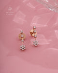 Rose gold earrings with diamond accents on a pink background, featuring Tattvva Diamonds logo.