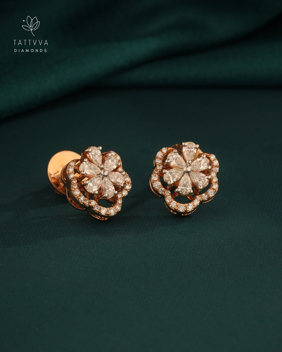 Rose gold earrings with diamond accents on a dark green fabric background, featuring Tattvva Diamonds logo.