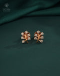 Rose gold earrings with diamond accents on a green fabric background, branded 'Tattvva Diamonds'.