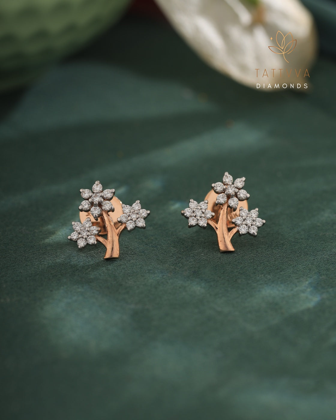 Pair of diamond earrings on a green leaf with 'Tattvva Diamonds' branding.