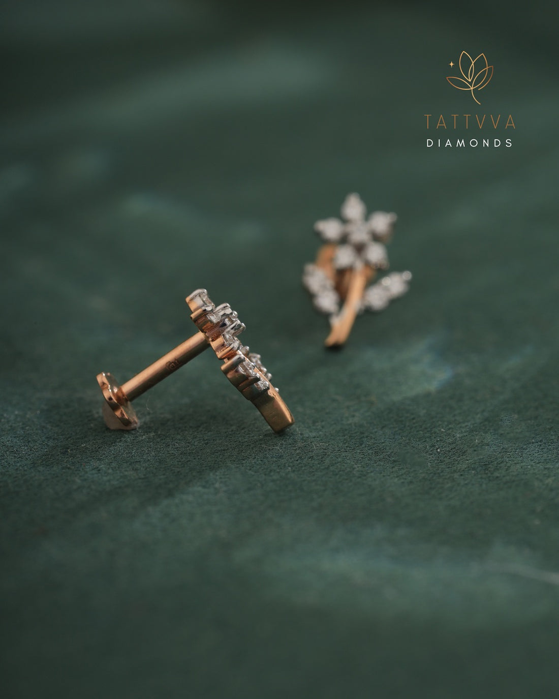 Pair of diamond earrings on a green leaf background with Tattvva Diamonds logo.